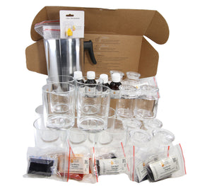 A collection of clear glass jars and candle cups along with wicks, wax, and other candle making supplies, with some items packaged in open boxes.